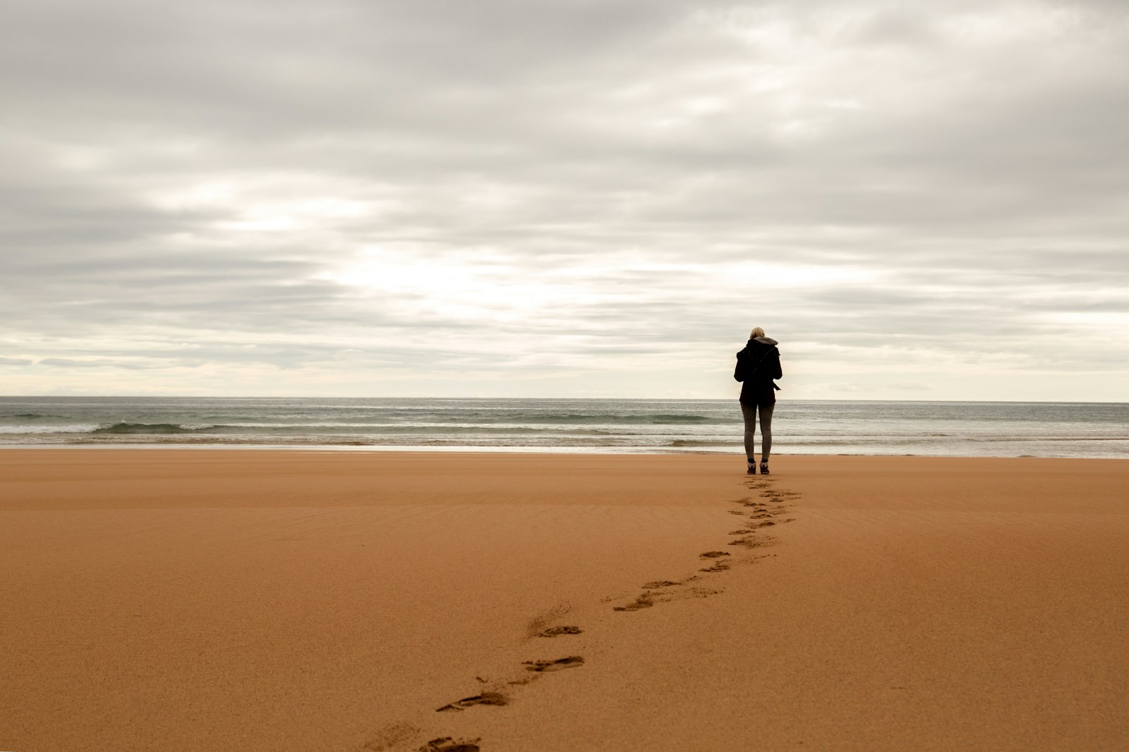Before: a person stands at the edge of the sea at the end of a line of footprints