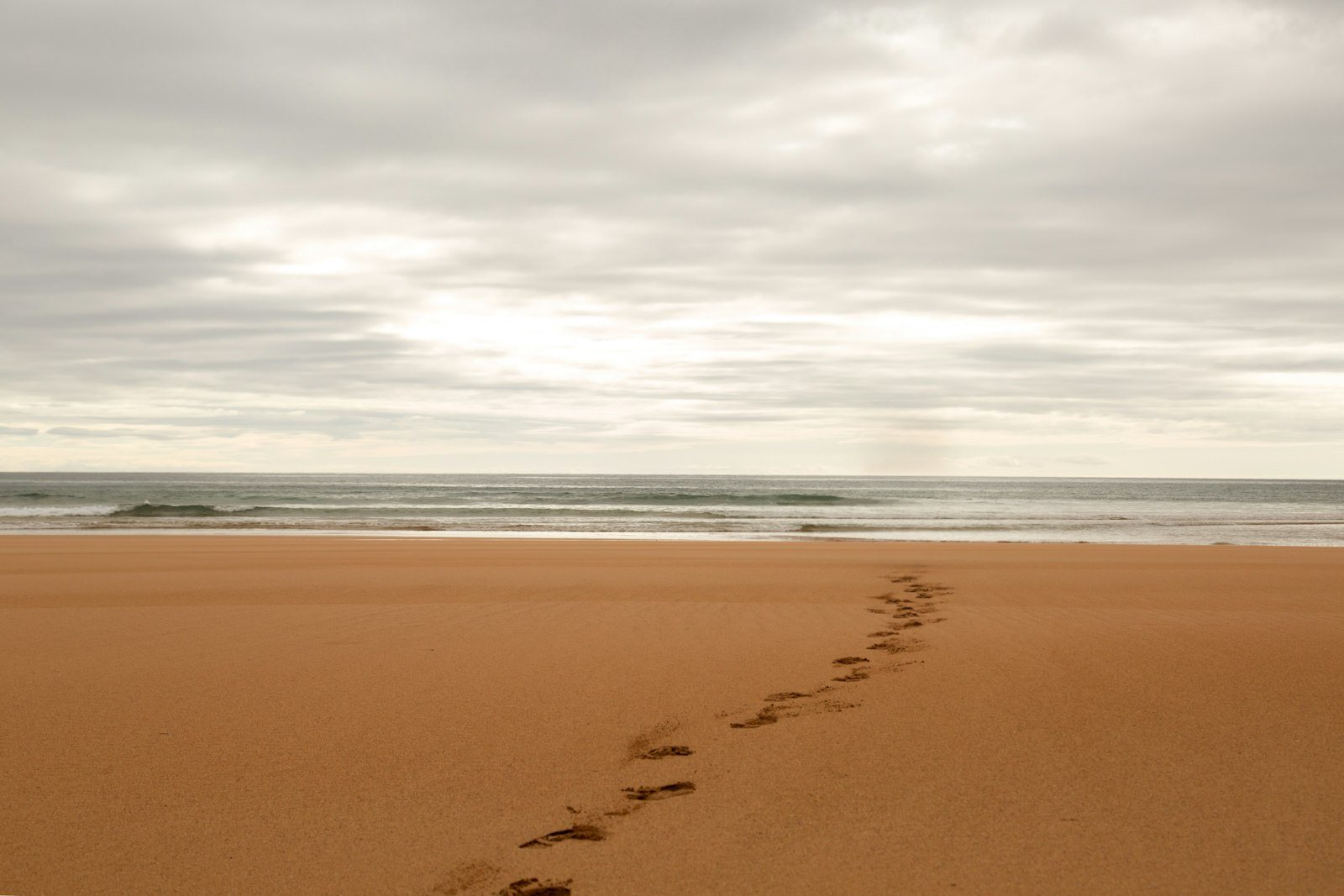 After: the person is gone, and the footprints lead to the empty shore